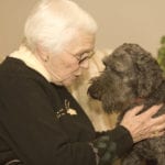 senior citizen with old dog before animal euthanasia in living room